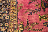 Close-up of the vintage Meshed carpet's detailed navy border alongside the magenta field's floral sprays.