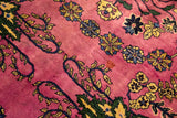 A small, period-correct stain shown on the deep magenta pile of a vintage floral carpet.
