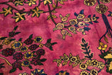 Time-softened magenta wool pile showing natural dye variations around floral motifs.