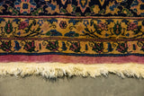 Detail of a vintage carpet's floral border with magenta edge, intact selvage, and ivory fringe.