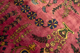 Vintage carpet detail with blue and gold floral sprays on a rich magenta hand-knotted pile.