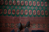 Plush hunter green Bokhara carpet featuring geometric gul medallions and intricate multi-banded border.