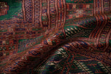 Sheen and texture of a vintage Bokhara rug with intricate rust, emerald, and navy gul designs.