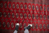 Close-up of the plush cherry red wool pile showing repeating gul medallions on a fine Bokhara rug.