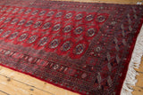 Lustrous cherry red wool pile and clean original fringe on a vintage Bokhara runner corner.