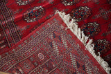 Corner of a fine Bokhara rug folded to show the plush pile, tight back weave, and original fringe.