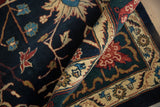A vintage Indian carpet is rolled, showing the thick navy pile and dragon-inspired ivory border.