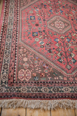 Corner of a vintage Persian Abadeh rug, showing dusty blush field, playful motifs, and fringe.