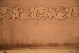 Embossed Art Deco curvilinear foliage carving on a vintage copper-toned rug.