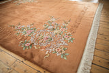 Embossed pastel florals and original cream fringe on a vintage copper Art Deco rug.