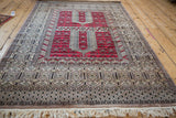 Angled view of a vintage Turkmen rug's red prayer niches and geometric serpent borders.
