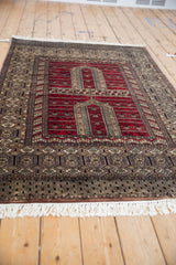 Low-angle view of a vintage Turkmen rug, highlighting the cherry red prayer design and intricate border.