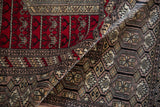 Serpent borders frame the contrasting red niche and silver geometric field of a vintage Turkmen rug.