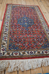 Vintage Persian Ardebil rug shown from a low angle, highlighting its full ivory fringe.