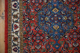 The vintage Ardebil rug's brick red and sapphire blue Herati design meets its detailed ivory main border.