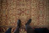 A look down at the dense wool pile and detailed floral lattice of a vintage Indian carpet in gold and burgundy.