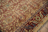Intricate floral vinery and palmette border detail on the vintage carpet's plush wool pile.
