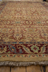 Low angle view of a vintage Indian rug highlighting its dense, high-luster wool pile and detailed floral border.