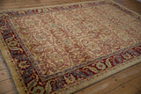 Corner of the vintage Indian carpet highlighting the scrolling leaf border in red, blue, and gold.