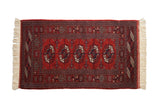 Vintage Bokhara rug runner in brick red with repeating geometric gul medallions and ivory accents.