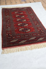 Angled view of a vintage Bokhara rug runner highlighting its traditional gul pattern and lustrous red pile.