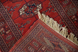 A vintage Bokhara rug corner folded to show the intricate back weave and plush ivory fringe.