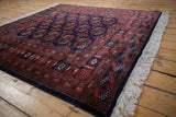 Angled view of a vintage Bokhara rug showing the lustrous wool pile and clean ivory fringe.