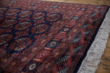 Angled view of a Bokhara rug's dense wool pile, detailed geometric border, and soft ivory fringe.