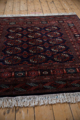 Angled view of a vintage Bokhara rug's corner highlighting the plush wool pile and ivory fringe.