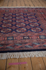 Low-angle view across a Bokhara rug, detailing the plush navy pile and ivory fringe.