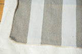 Modern grey and white striped flat weave rug corner, showing durable recycled polyester texture.