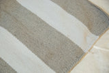 Hand-woven rug corner with alternating neutral beige and off-white stripes.