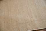 Blanched amber jute hand-woven rug detail, showcasing its supple, ribbed texture.