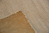 Amber Jute rug close-up, revealing its blanched hand-woven texture and supple fold.