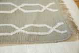 New Bo rug's hand-woven olive-green and white geometric pattern with fringe.