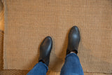 Cali New Carpet's natural jute tight weave texture, with feet for scale.