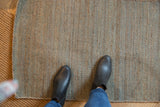 Hand-woven jute rug texture with subtle gray and blue tones, underfoot.