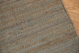 Modern hand-woven jute rug sample with natural, gray, and blue tones.