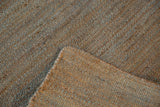 Hand-woven jute rug texture, with natural brown, gray, and blue tones at the folded corner.