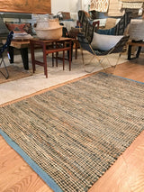 Clay rug's hand-woven texture, recycled leather and jute fibers, and blue border.