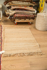 Detail of natural jute rug's hand-woven texture and fringed end.