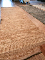 Textured plain weave jute rug showing natural striations and finished end.