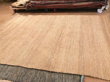 Natural jute rug with visible plain weave texture and varying light to dark striations.