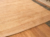 Natural jute rug detail: visible plain weave texture with subtle tonal striations.