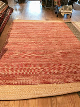 Textured hand-woven jute rug border, with reddish stripes transitioning to natural tone.