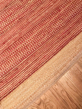 Handmade jute rug showcasing its textured red and natural beige diagonal weave and border.