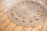 Hand-woven round jute rug showcasing concentric coiled pattern and natural texture.