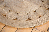 Braided jute rug with distinct coiled border pattern and subtle gray texture.
