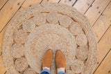 Natural hand-woven jute rug, highlighting braided texture and distinct circular patterns.