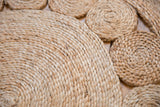 Natural hand-woven jute rug close-up, revealing braided coiled texture and patterns.